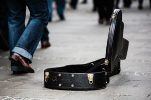 Image of people walking by an open guitar case.